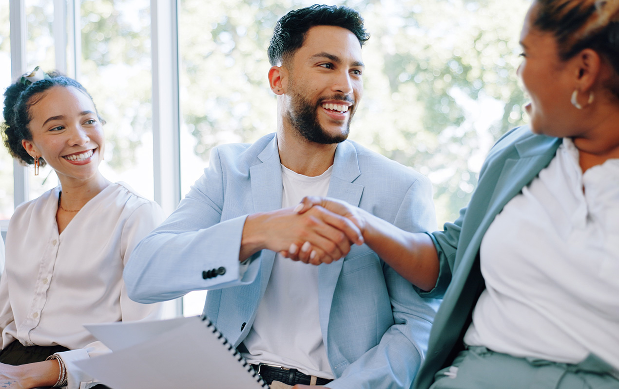 Two people in a waiting area shaking hands and introducing themselves.