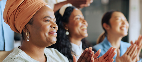 Diverse group of women applauding during a business meeting.