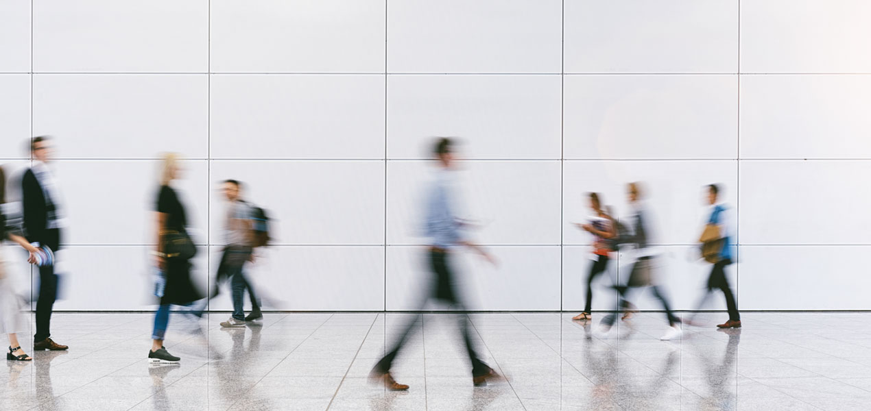 A blurred image of business people walking in a convention lobby or trades fair.