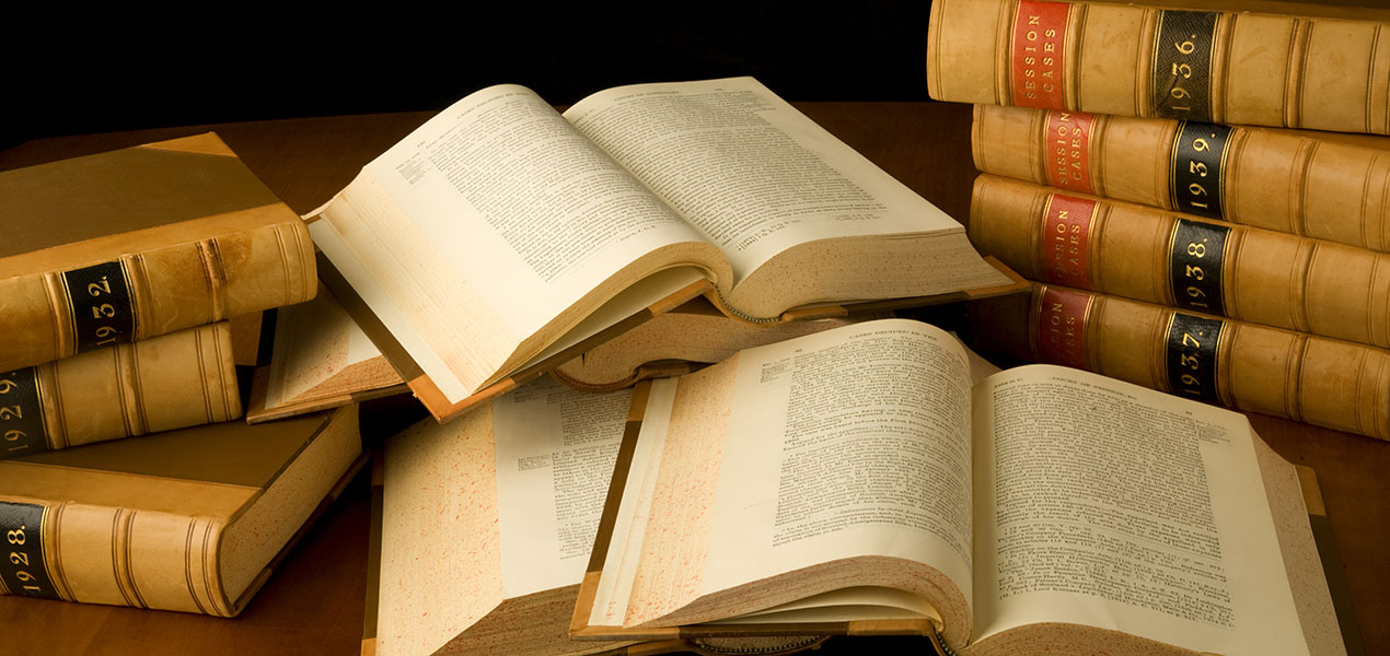 Scattered law books, some open and some closed, are sitting on a table.