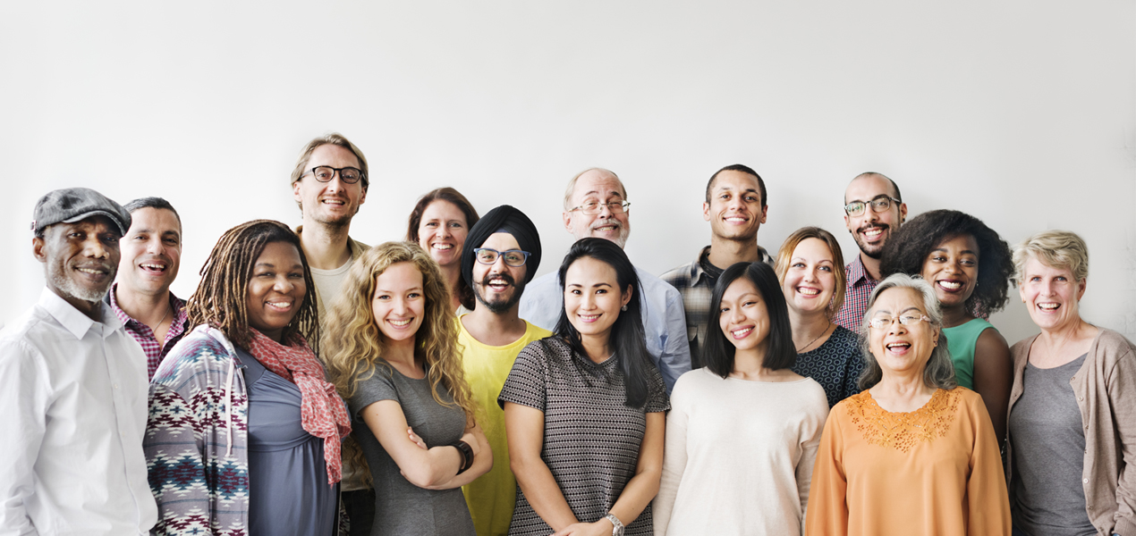 Diverse team standing and smiling against a white wall.Diverse team standing and smiling against a white wall.